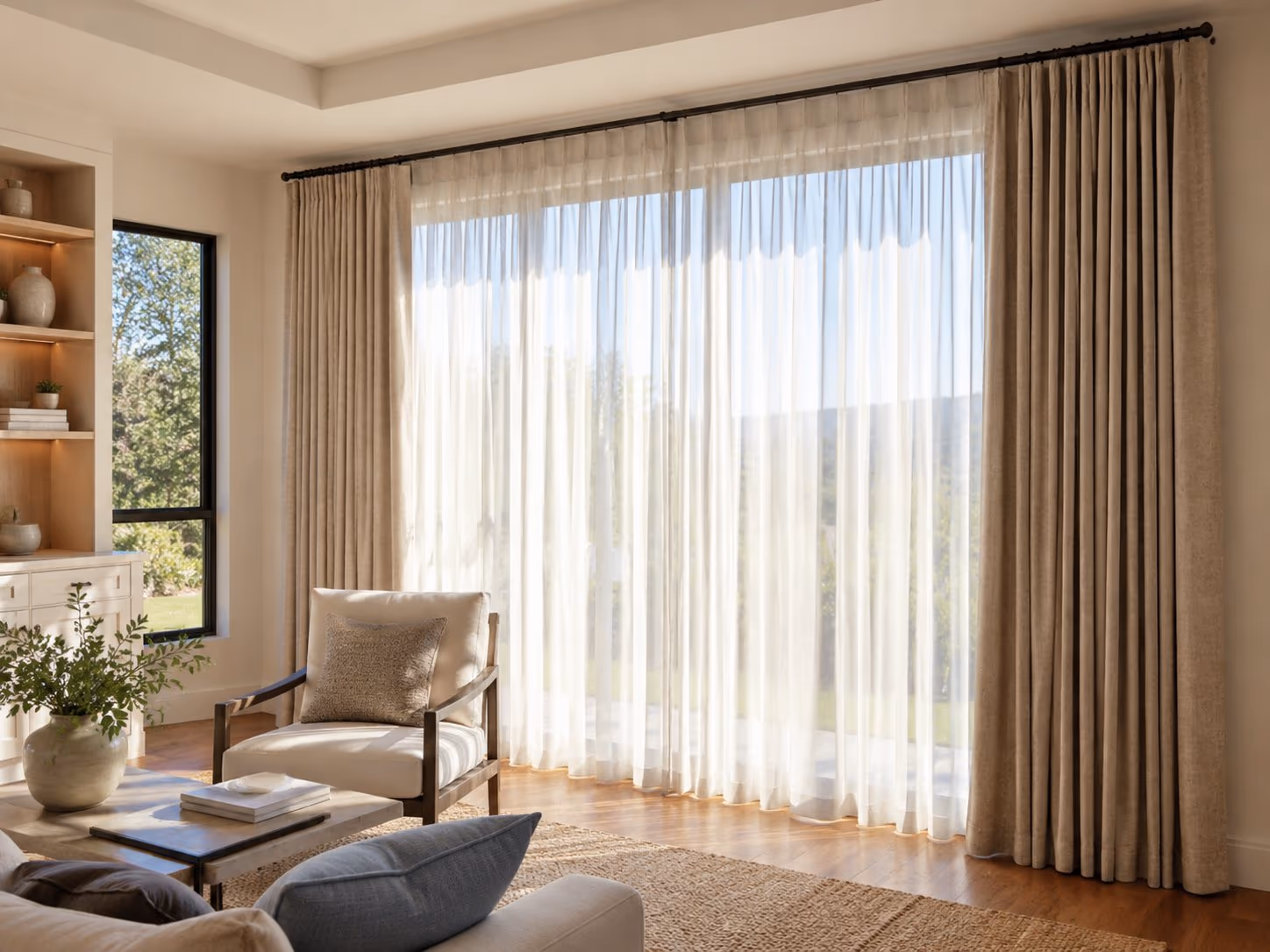 Pleated drapery panels and sheers hung on a black rod across a wide living-room window wall — Custom Drapery & Sheers installed by Discount Best Blinds of Santa Rosa, CA.